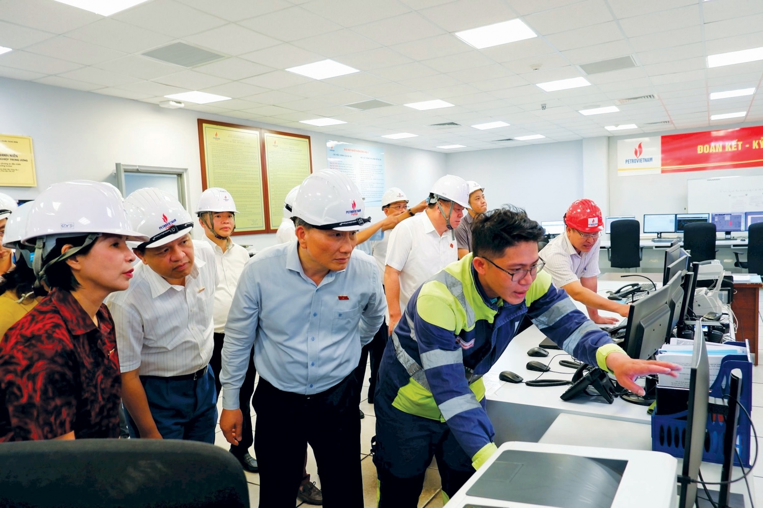Đoàn nghe báo cáo về các thông số kỹ thuật của nhà máy trong phòng điều khiển trung tâm