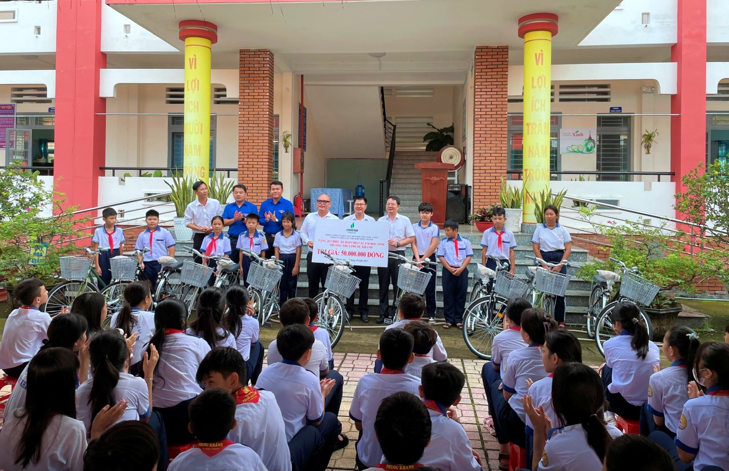 Đại diện xã Đại Phước, PV Power NT và Ban Giám hiệu Trường THCS Phước Khánh trao tặng xe đạp cho các em học sinh nghèo vượt khó