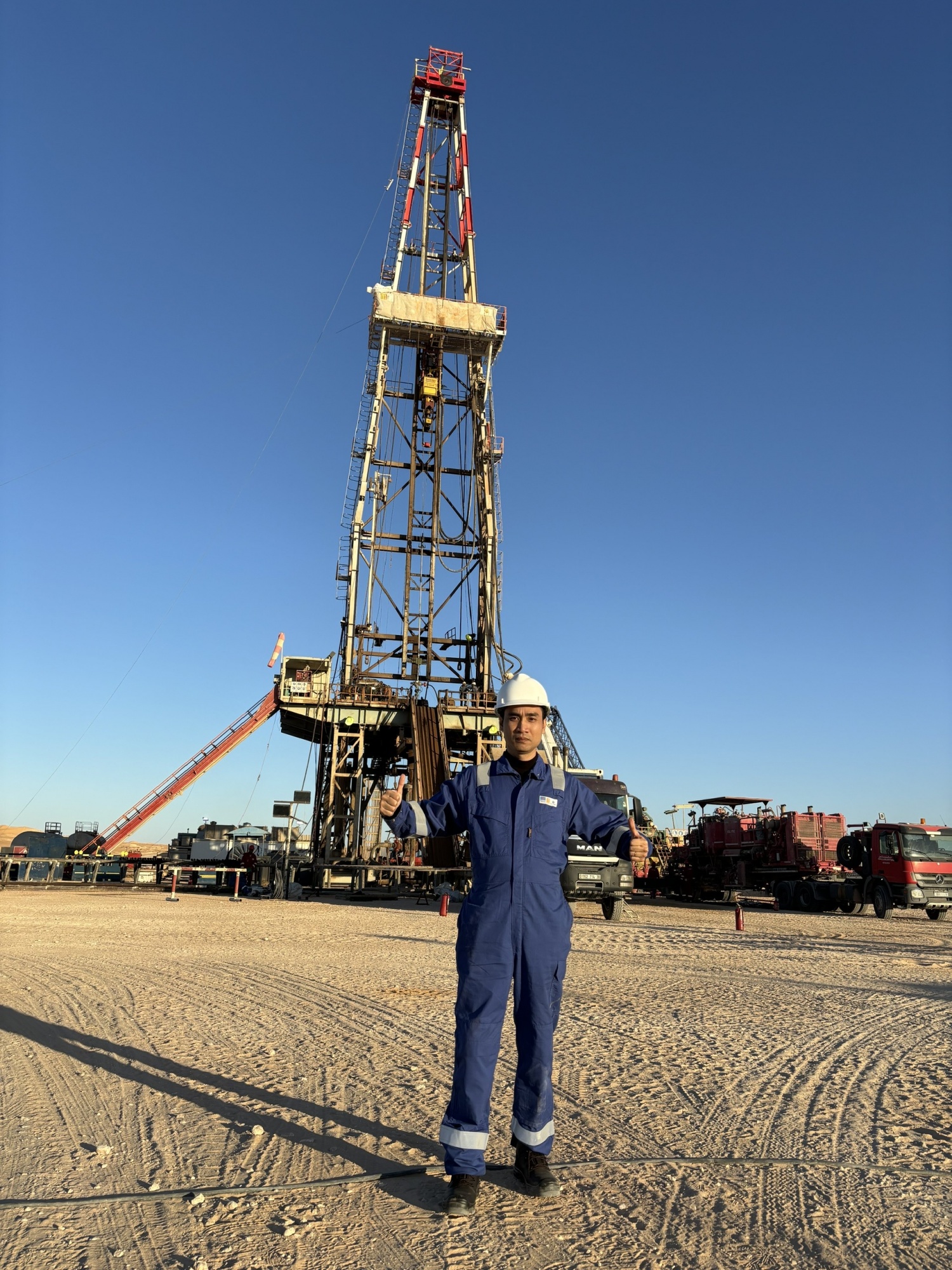 Anh Nguyễn Hoàng Đức đứng trước giàn khoan PV DRILLING 11 giữa biển cát tại sa mạc Sahara